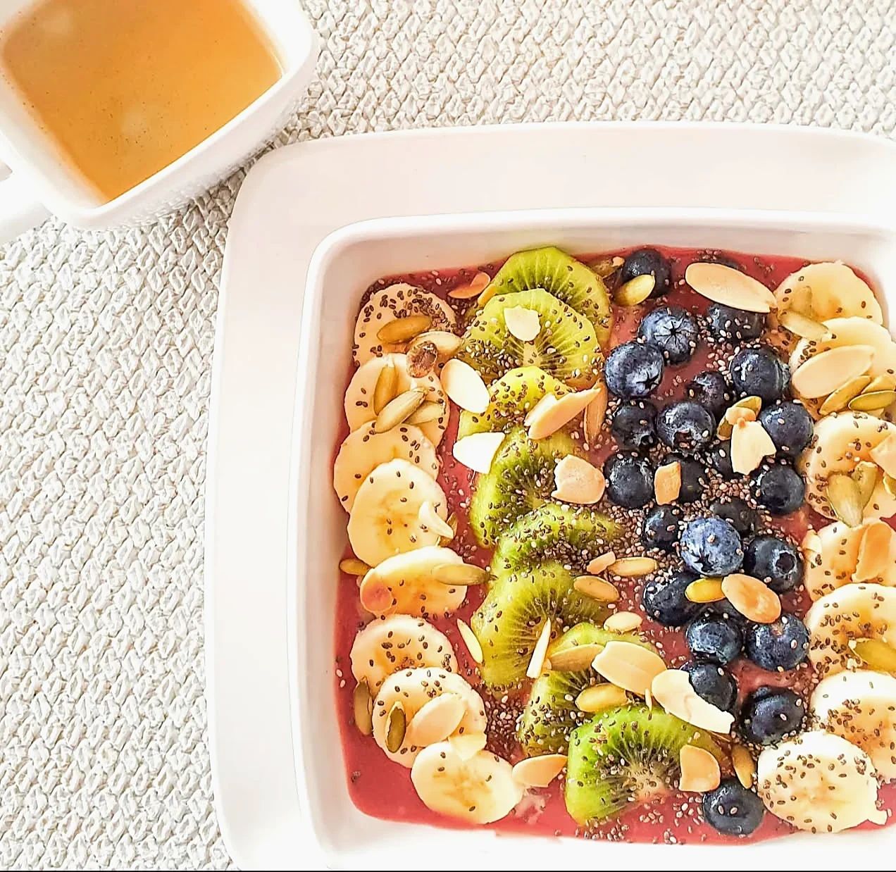 Bowl con rodajas de banano, kiwi, arándanos, semillas y almendras laminadas